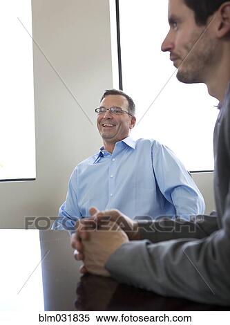 Stock Photography - Businessmen sitting in meeting. Fotosearch