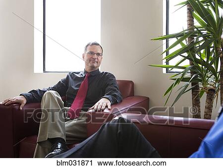 Stock Image - Businessmen talking in armchairs in office. Fotosearch