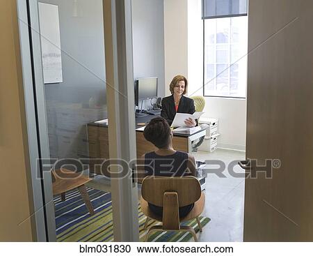 Stock Image - Businesswomen talking in office. Fotosearch