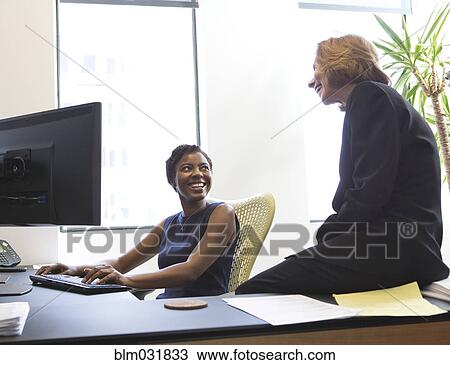 Stock Image - Businesswomen working together in office. Fotosearch