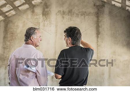 Stock Photograph - Caucasian architects talking near wall. Fotosearch