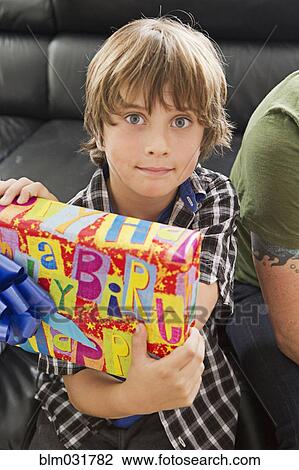 Stock Image - Caucasian boy holding birthday present. Fotosearch