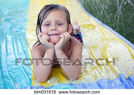 Stock Photograph - Caucasian boy smiling on water slide. Fotosearch