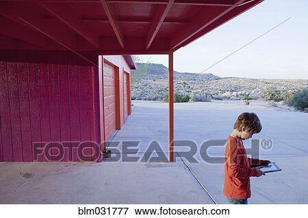Caucasian boy using tablet on concrete patio View Large Photo Image Stock Photo - Caucasian boy using tablet on concrete patio. Fotosearch