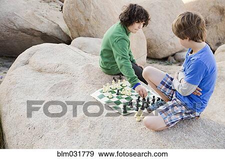 Stock Photo - Caucasian boys playing chess on boulder. Fotosearch