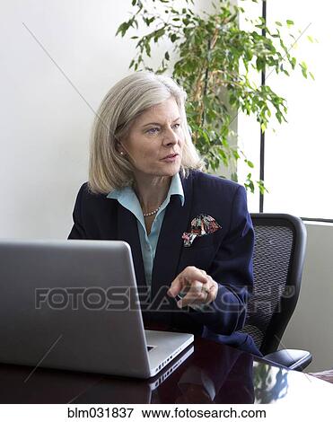 Stock Photo - Caucasian businesswoman talking at desk. Fotosearch