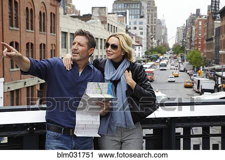 Stock Image - Caucasian couple holding map in city, New York City, New York, United States. Fotosearch