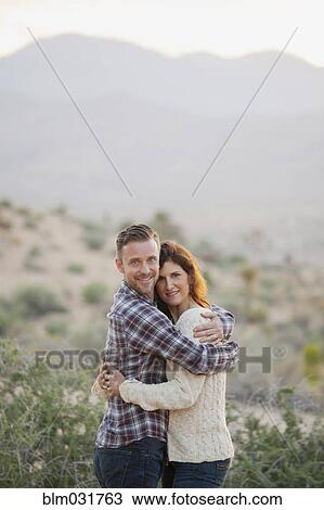 Stock Image - Caucasian couple hugging in desert. Fotosearch