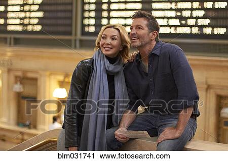 Stock Image - Caucasian couple reading train schedule in Grand Central Station, New York City, New York, United States. Fotosearch