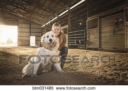 Stock Photography - Caucasian farmer smiling with dog in barn. Fotosearch