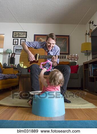 Stock Photo - Caucasian father playing guitar for daughter. Fotosearch