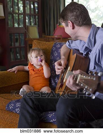 Stock Photograph - Caucasian father playing guitar for daughter. Fotosearch