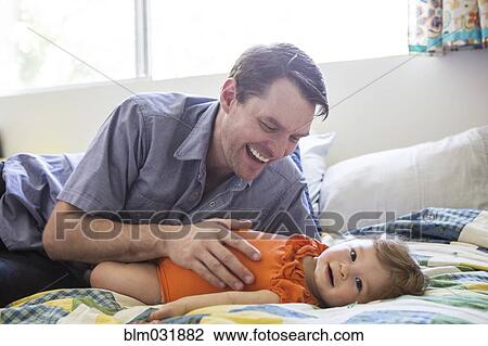 Caucasian father playing with daughter on bed View Large Photo Image Stock Image - Caucasian father playing with daughter on bed. Fotosearch