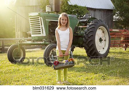 Stock Photo - Caucasian girl holding basket of flowers on farm. Fotosearch
