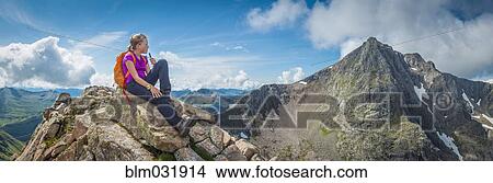 Picture - Caucasian girl sitting on rocky mountain. Fotosearch