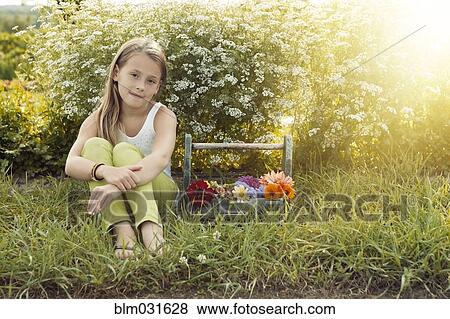 Stock Photo - Caucasian girl sitting with basket of flowers. Fotosearch