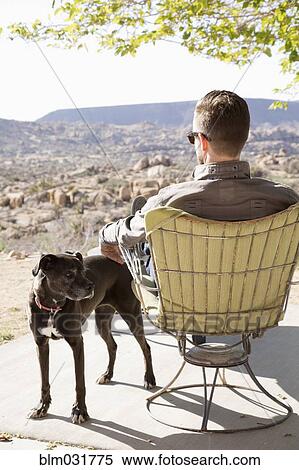 Stock Photography - Caucasian man and dog relaxing in desert. Fotosearch