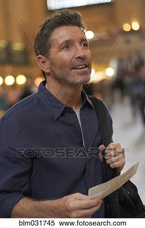 Stock Photography - Caucasian man reading train schedule in Grand Central Station, New York City, New York, United States. Fotosearch