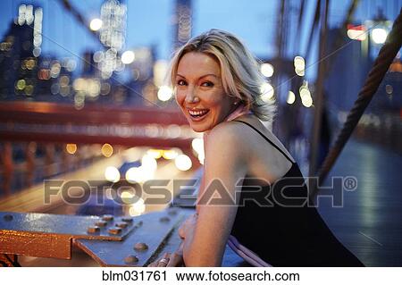 Stock Image - Caucasian woman leaning on railing on Brooklyn Bridge, New York City, New York, United States. Fotosearch