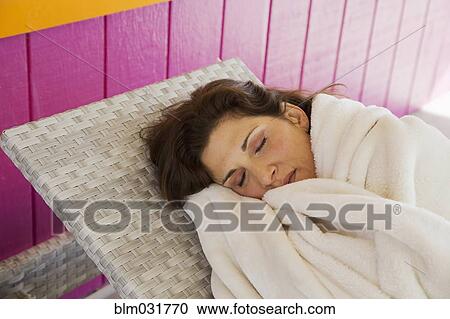 Stock Image - Caucasian woman napping on deck chair. Fotosearch