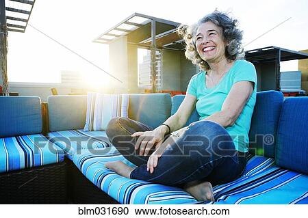Stock Image - Caucasian woman relaxing on urban rooftop. Fotosearch