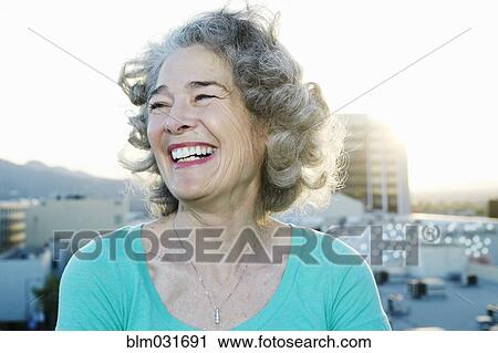 Stock Image - Caucasian woman smiling on urban rooftop. Fotosearch