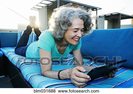 Stock Photo - Caucasian woman using digital tablet on urban rooftop. Fotosearch