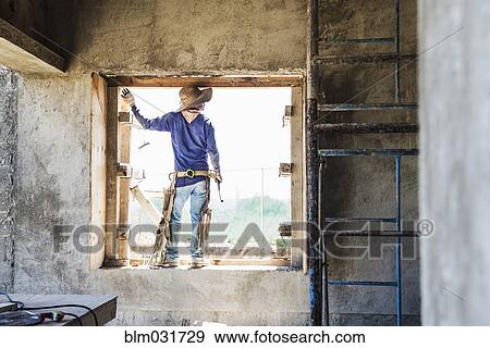 Stock Photo - Hispanic construction worker in window at construction site. Fotosearch