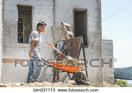 Hispanic construction worker pushing wheelbarrow at construction site View Large Photo Image Stock Image - Hispanic construction worker pushing wheelbarrow at construction site. Fotosearch