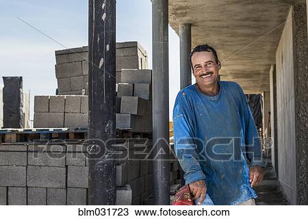 Stock Image - Hispanic construction worker smiling at construction site. Fotosearch