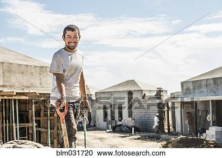 Stock Image - Hispanic construction worker with shovel at construction site. Fotosearch