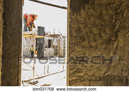 Stock Photo - Hispanic construction workers at construction site. Fotosearch