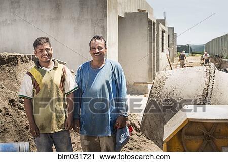 Stock Image - Hispanic construction workers smiling at construction site. Fotosearch