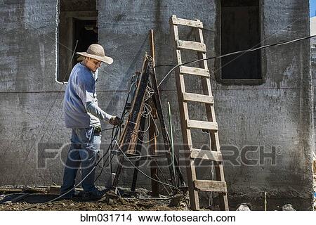 Picture - Hispanic worker with wires at construction site. Fotosearch