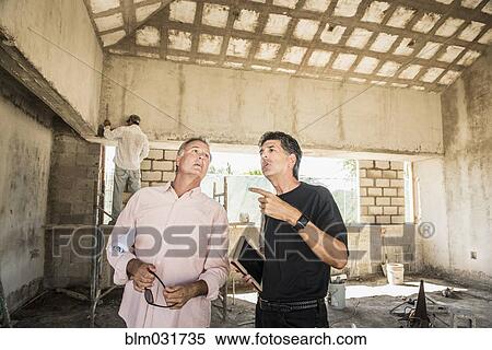 Stock Photography - Men talking at construction site. Fotosearch
