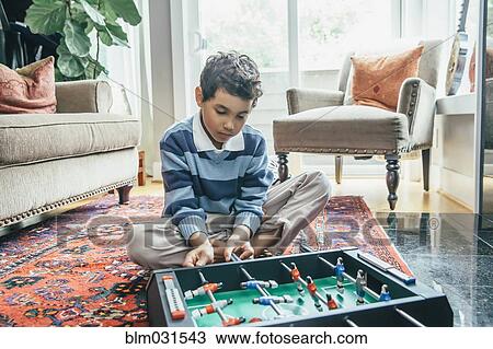 Mixed race boy playing foosball on living room floor View Large Photo Image Stock Image - Mixed race boy playing foosball on living room floor. Fotosearch