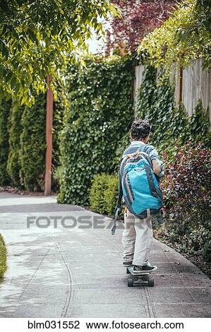 Stock Image - Mixed race boy riding skateboard on sidewalk. Fotosearch