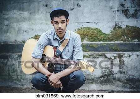 Mixed race boy with guitar crouching on urban sidewalk View Large Photo Image Stock Photo - Mixed race boy with guitar crouching on urban sidewalk. Fotosearch