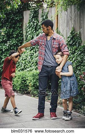Stock Photograph - Mixed race brothers and sister playing on suburban sidewalk. Fotosearch