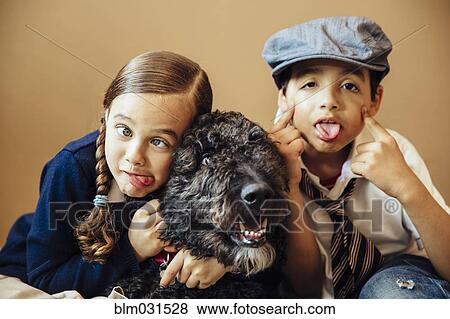 Stock Photo - Mixed race children making faces with dog. Fotosearch