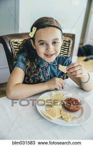 Mixed race girl eating chips and salsa at table View Large Photo Image Stock Image - Mixed race girl eating chips and salsa at table. Fotosearch