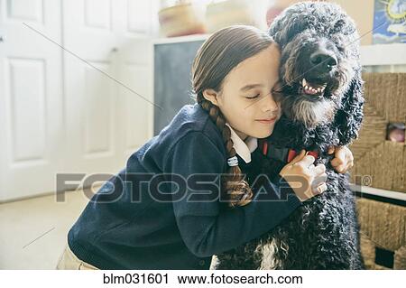 Stock Image - Mixed race girl hugging dog. Fotosearch