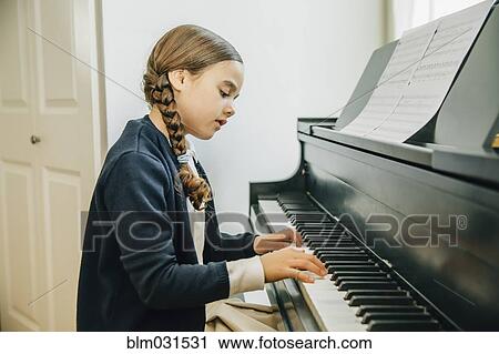 Stock Image - Mixed race girl playing piano. Fotosearch