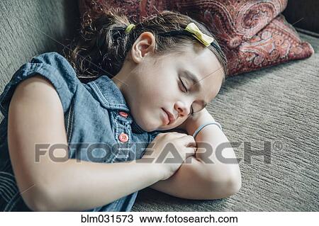 Stock Image - Mixed race girl sleeping on sofa. Fotosearch