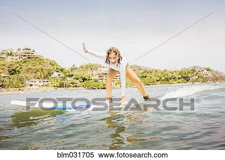 Stock Photography - Mixed race girl surfing in waves. Fotosearch