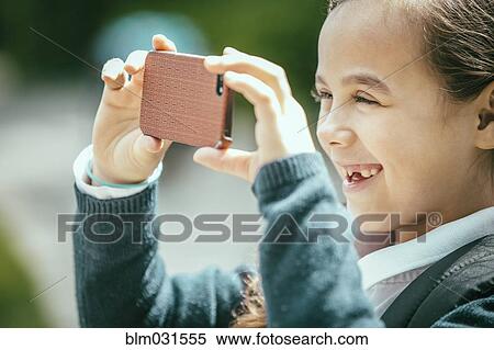 Stock Photography - Mixed race girl using cell phone outdoors. Fotosearch