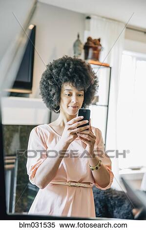 Mixed race woman using cell phone in living room View Large Photo Image Stock Photography - Mixed race woman using cell phone in living room. Fotosearch