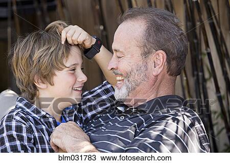 Stock Image - Older Caucasian man relaxing with grandson outdoors. Fotosearch