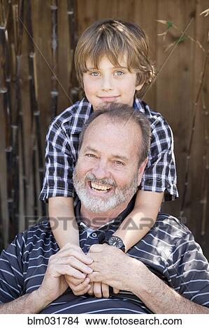 Picture - Older Caucasian man smiling with grandson outdoors. Fotosearch