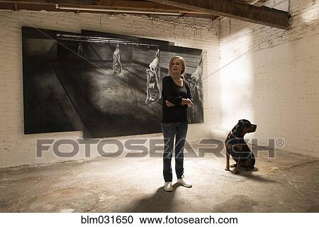 Stock Image - Woman and dog standing in art gallery. Fotosearch